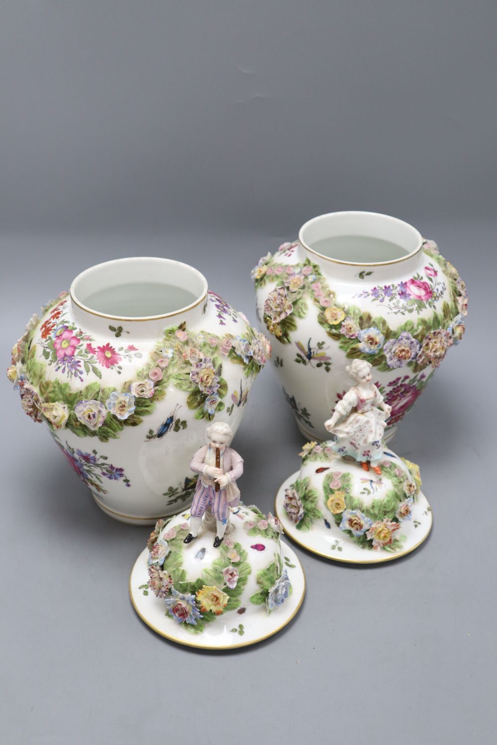 A pair of Augustus Rex floral encrusted porcelain vases and covers and a similar putti centrepiece, tallest 37cm